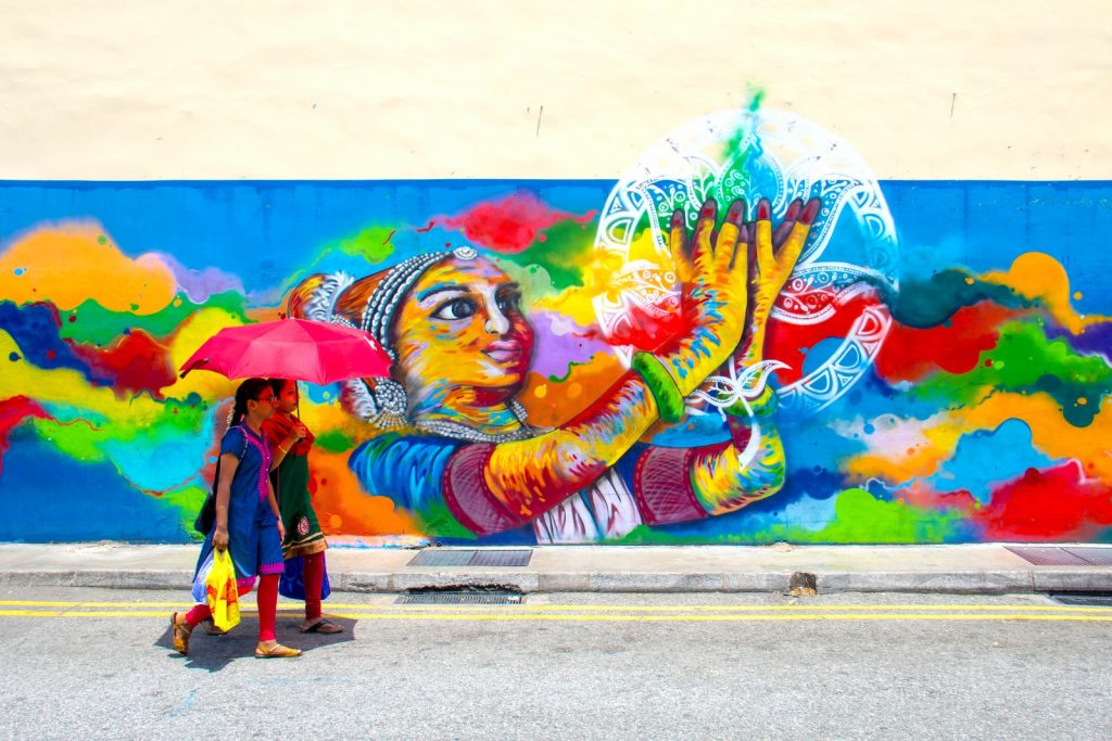 Street art graffiti Singapore two girl holding umbrella while walking beside graffiti