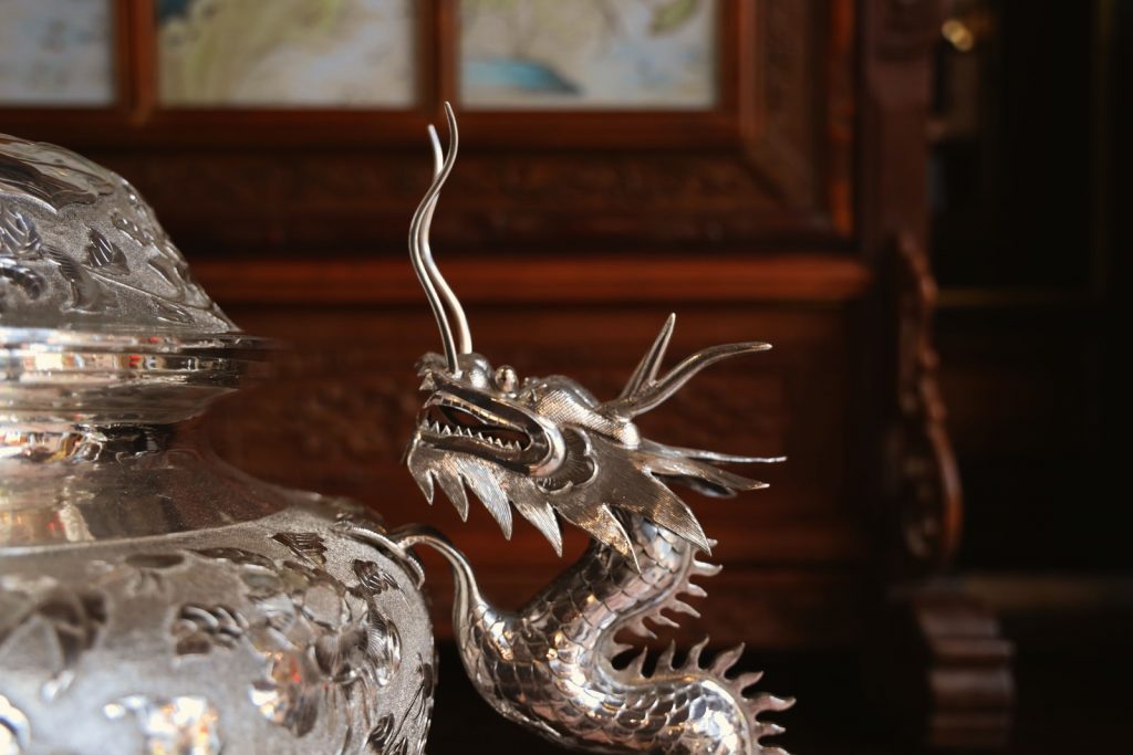 Peranakan  silver dragon figurine on brown wooden table